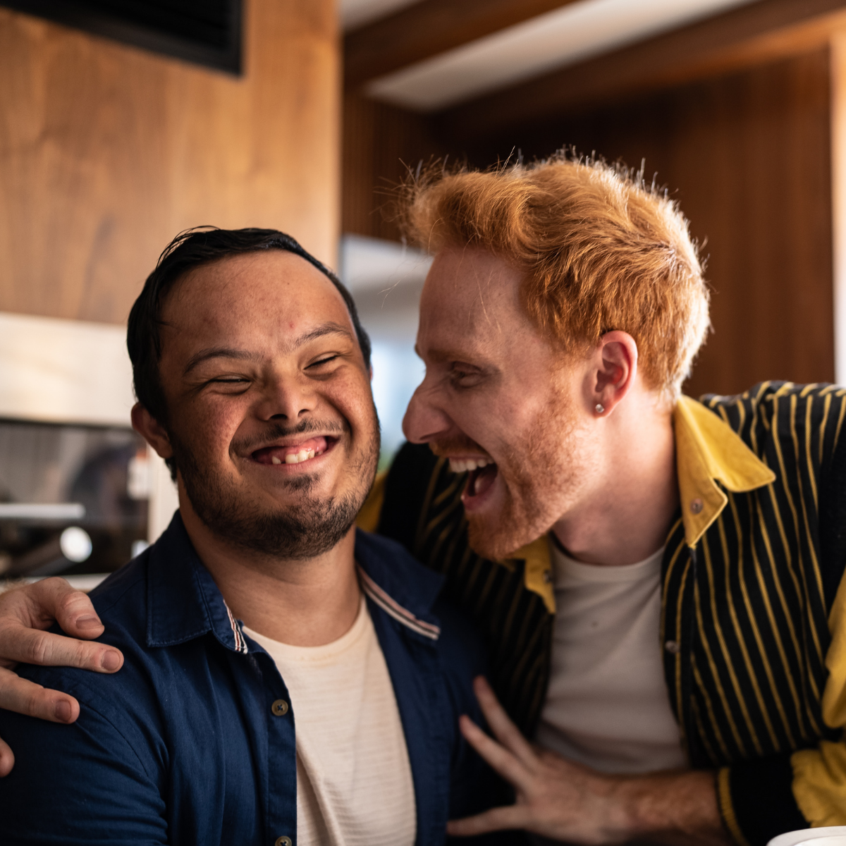 Two men, one with Down syndrome, laugh together.